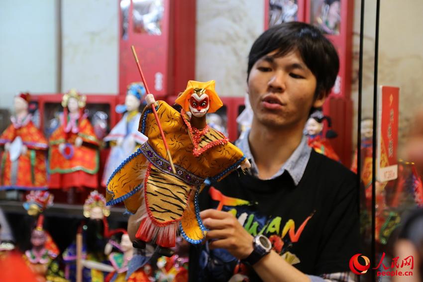 传统艺术中心一家商店店员展示傀儡戏表演方法。闫嘉琪 摄影