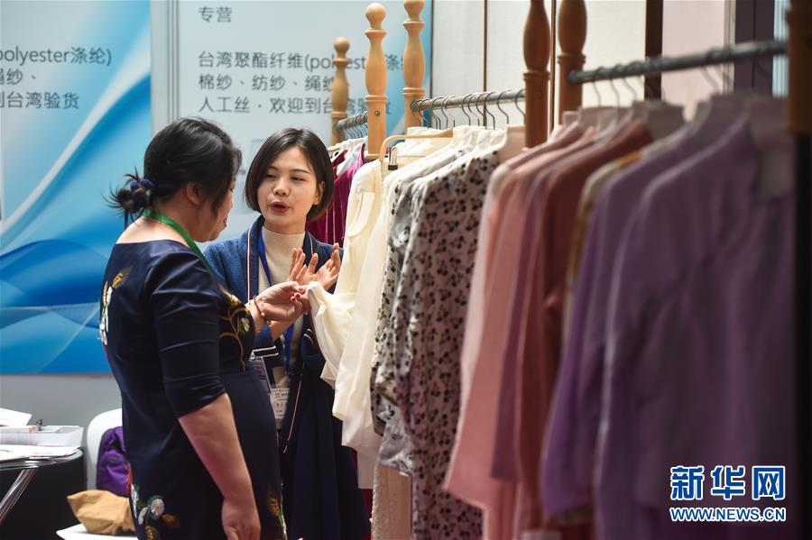 4月18日，客商（右）在博覽會上介紹紡織面料。