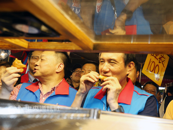 马英九（前右）8日晚间南下陪国民党提名台南市长参选人高思博（前左）到台南市中西区武圣夜市扫街拜票，开心品尝小吃。（图片来源：台湾“中央社”）
