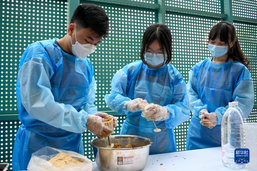 7月18日，在成都大熊猫繁育研究基地，参加体验营的两岸大学生在体验制作大熊猫食用的窝窝头，将和好的面粉塞入模具中。新华社记者 胥冰洁 摄